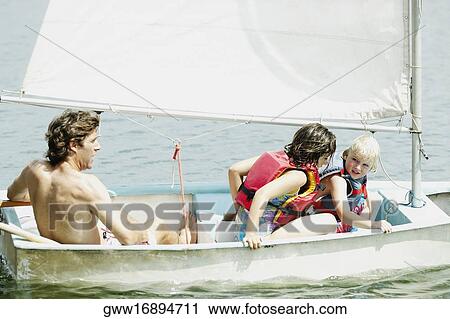 Rear view of a mid adult man with his children in a sailboat View Large Photo Image Stock Image - Rear view of a mid adult man with his children in a sailboat. Fotosearch