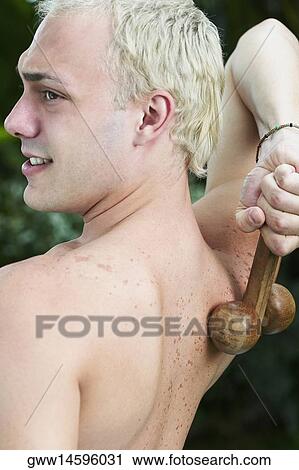 Rear view of a young man massaging his back with a wooden back massager View Large Photo Image Stock Image - Rear view of a young man massaging his back with a wooden back massager. Fotosearch