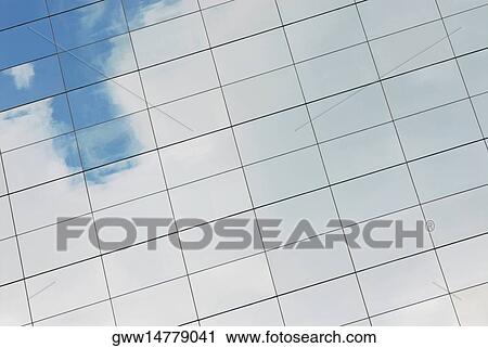 Stock Image - Reflection of sky and clouds on a building. Fotosearch