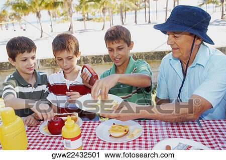 Senior man giving potato chips to his grandsons View Large Photo Image Stock Image - Senior man giving potato chips to his grandsons. Fotosearch