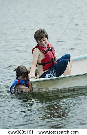 Side profile of a boy sitting in a boat with his friend swimming beside him View Large Photo Image Stock Image - Side profile of a boy sitting in a boat with his friend swimming beside him. Fotosearch