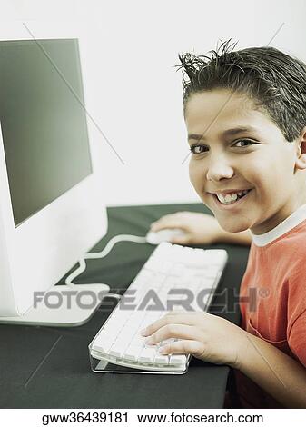 Stock Image - Side profile of a boy working on a computer. Fotosearch