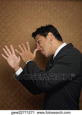 Stock Image - Side profile of a businessman pulling his face. Fotosearch