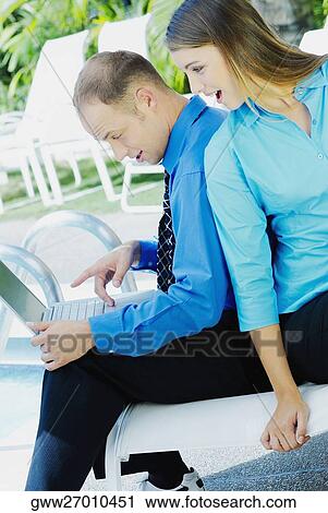 Side profile of a businessman using a laptop with a teenage girl sitting behind him View Large Photo Image Stock Image - Side profile of a businessman using a laptop with a teenage girl sitting behind him. Fotosearch