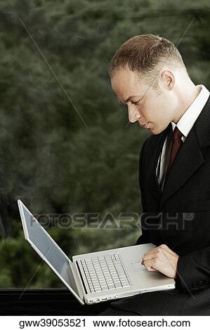 Stock Image - Side profile of a businessman using a laptop. Fotosearch