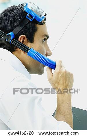 Stock Image - Side profile of a businessman wearing a snorkel. Fotosearch