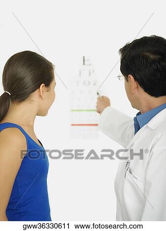 Side profile of a male doctor showing an eye chart to a female patient View Large Photo Image Stock Image - Side profile of a male doctor showing an eye chart to a female patient. Fotosearch