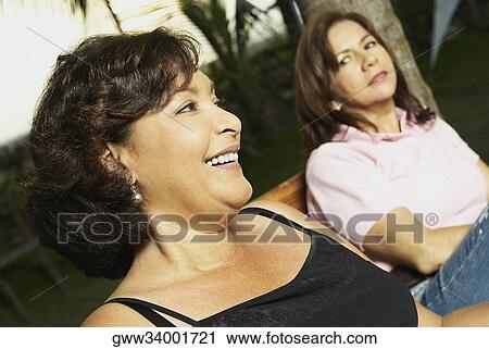 Side profile of a mature woman sitting with her friend and smiling View Large Photo Image Stock Image - Side profile of a mature woman sitting with her friend and smiling. Fotosearch