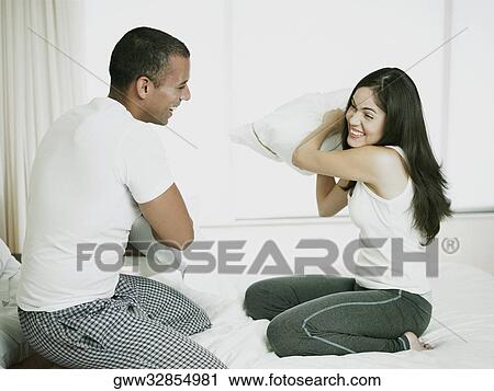 Side profile of a mid adult man with a young woman having a pillow fight on the bed View Large Photo Image Stock Image - Side profile of a mid adult man with a young woman having a pillow fight on the bed. Fotosearch