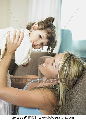 Side profile of a mid adult woman picking up her daughter and smiling View Large Photo Image Stock Image - Side profile of a mid adult woman picking up her daughter and smiling. Fotosearch