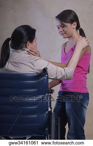 Side profile of a teenage girl standing beside her mother in a wheelchair View Large Photo Image Stock Image - Side profile of a teenage girl standing beside her mother in a wheelchair. Fotosearch