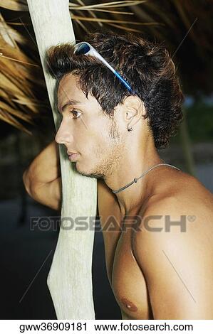 Side profile of a young man leaning against a wooden pole View Large Photo Image Stock Image - Side profile of a young man leaning against a wooden pole. Fotosearch