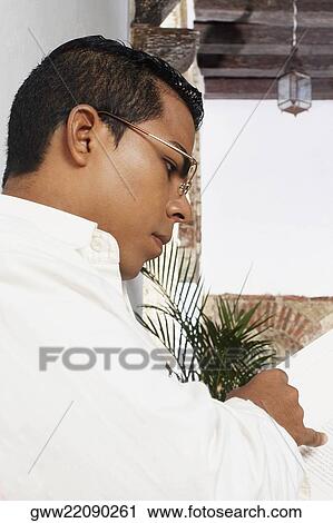 Stock Image - Side profile of a young man reading a book. Fotosearch