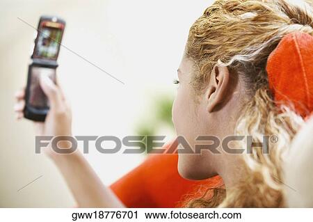 Side profile of a young woman looking at a mobile phone View Large Photo Image Stock Image - Side profile of a young woman looking at a mobile phone. Fotosearch