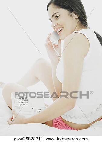 Stock Image - Side profile of a young woman using a telephone. Fotosearch
