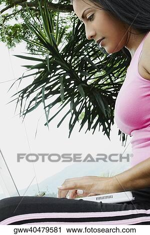 Side profile of a young woman using a laptop View Large Photo Image Stock Image - Side profile of a young woman using a laptop. Fotosearch
