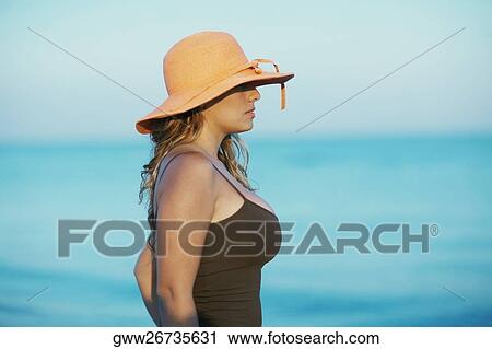 Side profile of a young woman wearing a hat View Large Photo Image Stock Image - Side profile of a young woman wearing a hat. Fotosearch