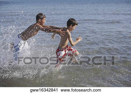 Teenage boy and a boy playing in the sea View Large Photo Image Stock Image - Teenage boy and a boy playing in the sea. Fotosearch