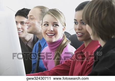 Stock Image - Three young women and two young men sitting side by side. Fotosearch