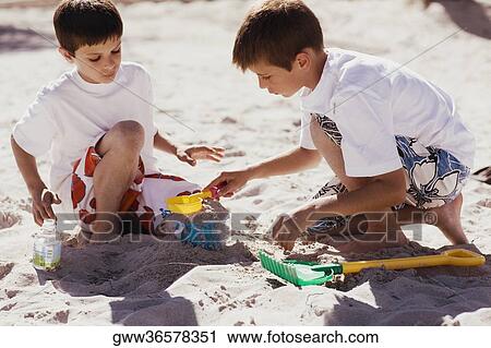 Two boys playing with sand pail and shovel on the beach View Large Photo Image Stock Image - Two boys playing with sand pail and shovel on the beach. Fotosearch