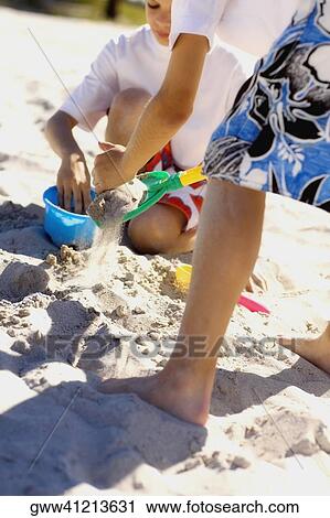 Two boys playing with sand pail and shovel on the beach View Large Photo Image Stock Image - Two boys playing with sand pail and shovel on the beach. Fotosearch