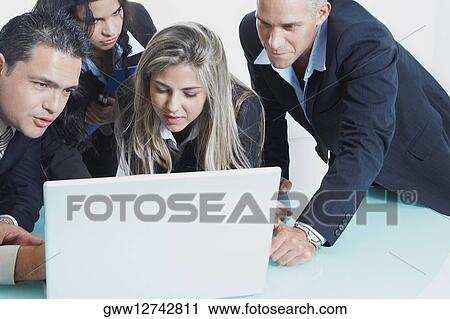 Two businessmen and two businesswomen in front of a laptop View Large Photo Image Stock Image - Two businessmen and two businesswomen in front of a laptop. Fotosearch