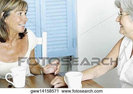 Stock Image - Two senior women looking at each other and smiling. Fotosearch