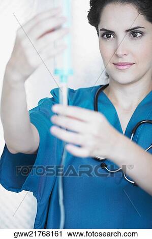 Young female doctor looking at an iv drip View Large Photo Image Stock Image - Young female doctor looking at an iv drip. Fotosearch