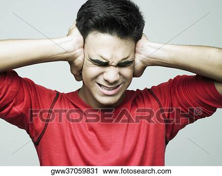 Stock Image - Young man covering his ears. Fotosearch