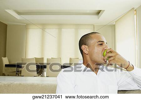 Young man eating a granny smith apple View Large Photo Image Stock Image - Young man eating a granny smith apple. Fotosearch
