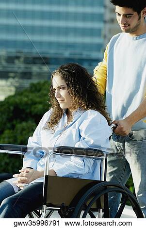 Young man pushing a wheelchair with a young woman View Large Photo Image Stock Image - Young man pushing a wheelchair with a young woman. Fotosearch