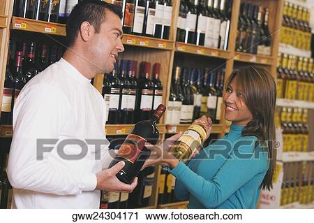 Young woman and a mid adult man choosing wine in a wine shop View Large Photo Image Stock Image - Young woman and a mid adult man choosing wine in a wine shop. Fotosearch