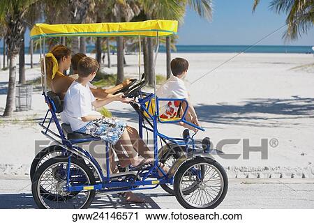 Stock Image - Young woman and three boys in a buggy. Fotosearch