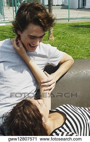 Young woman lying on a bench resting her head in the lap of a young man View Large Photo Image Stock Image - Young woman lying on a bench resting her head in the lap of a young man. Fotosearch