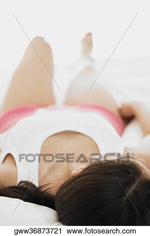 Stock Image - Young woman lying on the bed. Fotosearch