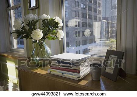 Books and a flower vase on a cabinet near a window View Large Photo Image Stock Image - Books and a flower vase on a cabinet near a window. Fotosearch