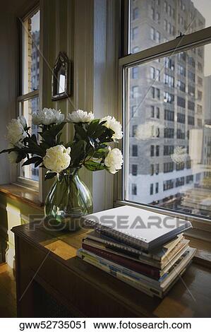Books and a flower vase on a cabinet near a window View Large Photo Image Stock Image - Books and a flower vase on a cabinet near a window. Fotosearch