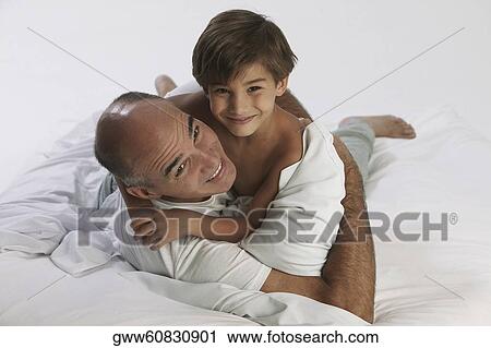 Boy lying on the bed with his father View Large Photo Image Stock Image - Boy lying on the bed with his father. Fotosearch