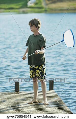 Boy standing on a pier and holding a fishing net View Large Photo Image Stock Image - Boy standing on a pier and holding a fishing net. Fotosearch
