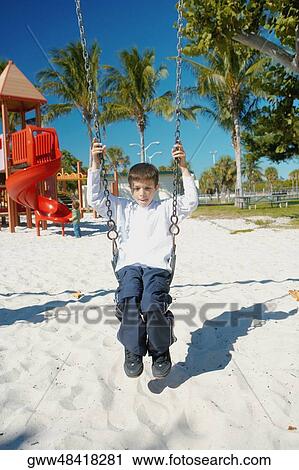Boy swinging on a swing View Large Photo Image Stock Image - Boy swinging on a swing. Fotosearch