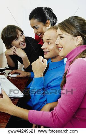 Businessman and three businesswomen sitting in front of computer and smiling View Large Photo Image Stock Image - Businessman and three businesswomen sitting in front of computer and smiling. Fotosearch