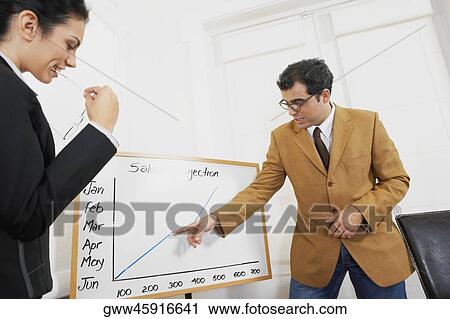 Stock Image - Businessman giving a graph presentation to a businesswoman. Fotosearch