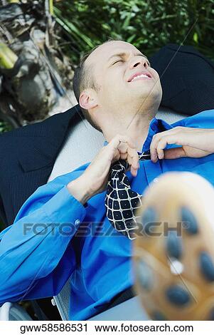 Businessman reclining on a lounge chair and loosening his tie View Large Photo Image Stock Image - Businessman reclining on a lounge chair and loosening his tie. Fotosearch