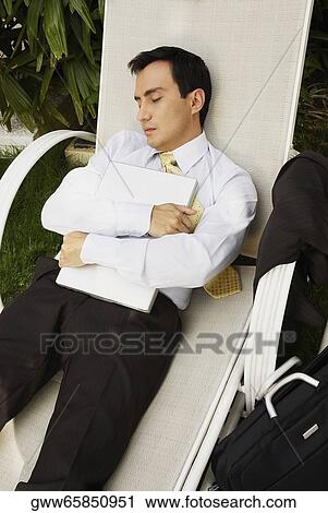 Stock Image - Businessman sleeping on a lounge chair. Fotosearch