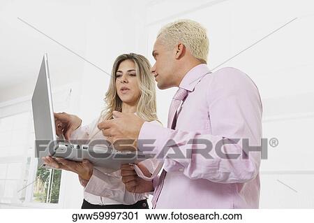 Stock Image - Businesswoman and a businessman using a laptop. Fotosearch