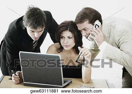 Businesswoman and two businessmen looking at a laptop View Large Photo Image Stock Image - Businesswoman and two businessmen looking at a laptop. Fotosearch