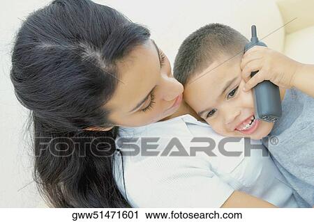 Close-up of a boy talking on a mobile phone with his mother beside him View Large Photo Image Stock Image - Close-up of a boy talking on a mobile phone with his mother beside him. Fotosearch