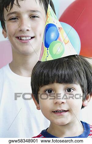 Close-up of a boy wearing a birthday hat in front of another View Large Photo Image Stock Image - Close-up of a boy wearing a birthday hat in front of another. Fotosearch