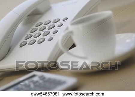 Stock Image - Close-up of a calculator and a tea cup near a telephone. Fotosearch