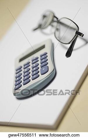 Stock Image - Close-up of a calculator with a pair of eyeglasses on a notepad. Fotosearch